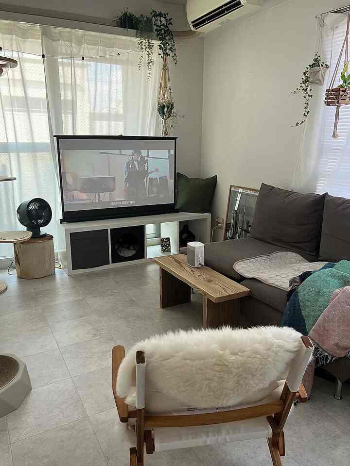 Bright beige and brown toned living room featuring a central projector screen and a 3-person sofa, creating a cozy home cinema setup