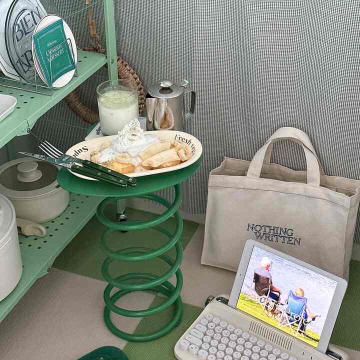 緑とベージュの色調のキッチン、チェック柄のカーペットとデザート皿が配置されたスプリングスタイルのサイドテーブルがある居心地の良いインテリア