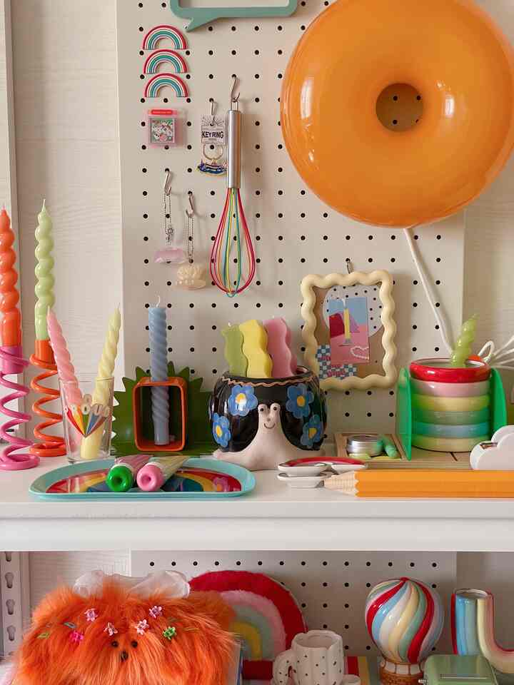 Colorful interior with white shelves featuring orange accent lighting, spiral candles, and kitchen utensils creating a playful atmosphere