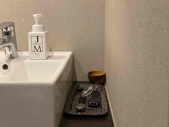 白い洗面台と黒いトレイが置かれた玄関の洗面スペース