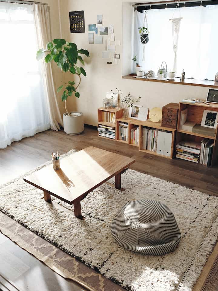 Natural wood tones and beige hues in a living room featuring a low wooden table, cushion, and bookshelf, creating a cozy atmosphere