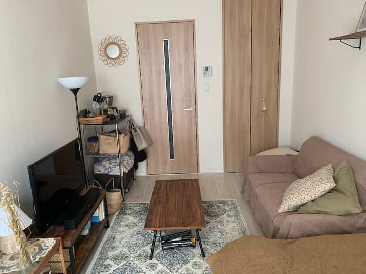 ベージュと木目調の小さなリビング、ソファと木製コーヒーテーブルが配置された雰囲気のあるインテリア