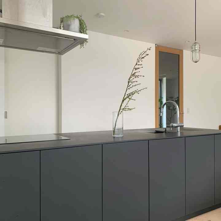 白と黒のモダンなキッチン、センターのシンプルでナチュラルな空間に透明な花瓶と枝が配置された印象的なインテリア