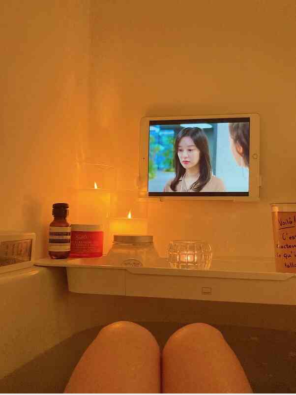 暖かい白色系のバスルーム、浴槽に座りキャンドルとタブレットを楽しむ落ち着いたリラックス空間