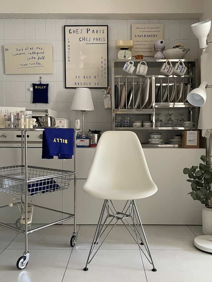 白とメタリックの色調のキッチン、中央に配置されたイームズチェアとシンプルで清潔感のあるインテリア