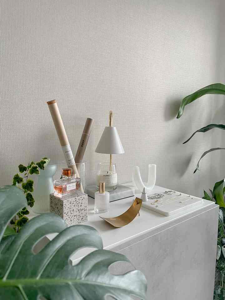 ベージュとアイボリーの色調のリビング、植物やキャンドル、ミニマルな照明が配置された印象的な空間