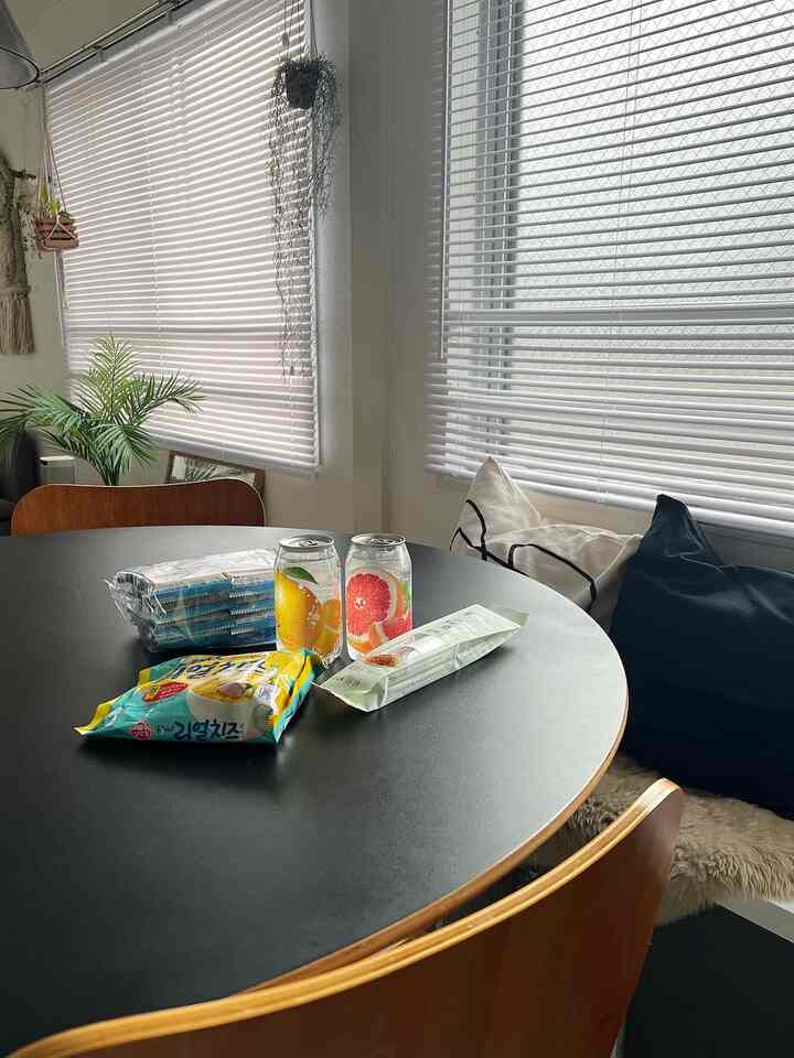 Natural dining room featuring black wood-tone dining table and chairs, with white blinds covering windows