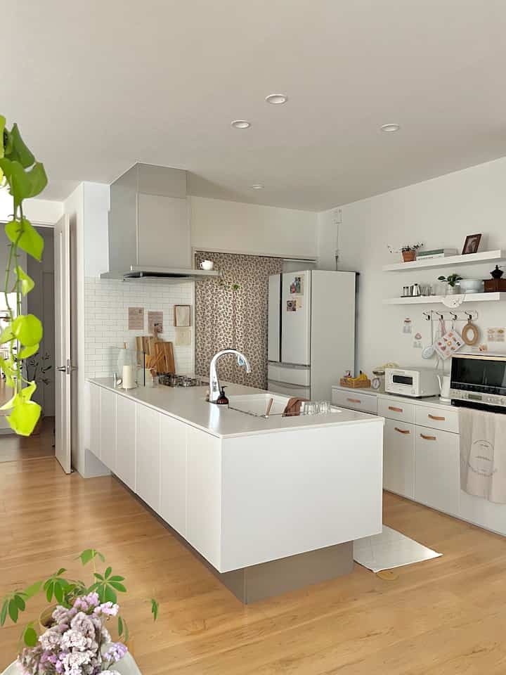 白と木目調のキッチン、広いキッチンアイランドと収納が整った雰囲気のあるインテリア