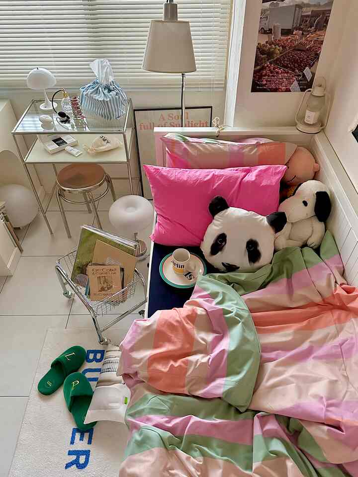 Bedroom in pink and white tones featuring cute panda cushions and colorful bedding creating a cozy atmosphere