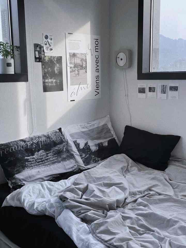 Monotone black and white bedroom for a single household featuring a bed, nightstand, and wall posters in a modern setting