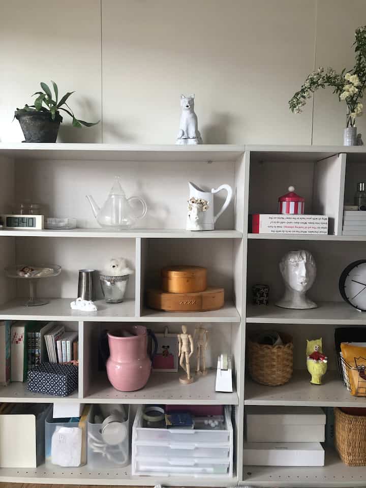 白を基調とした棚の空間、多様なオブジェと本が配置されたシンプルでナチュラルな雰囲気のインテリア