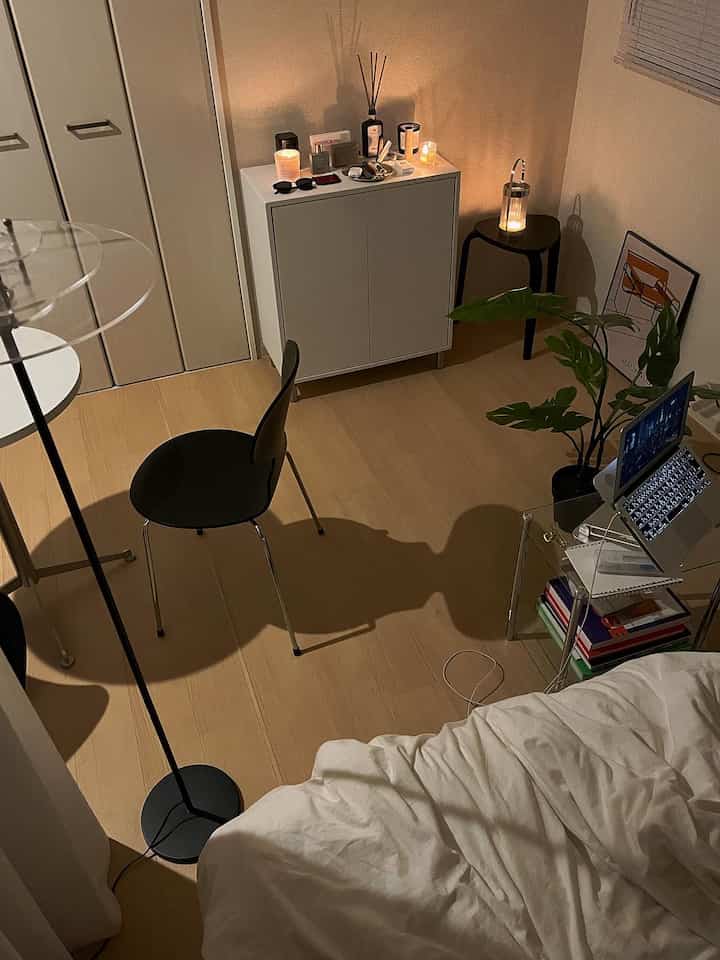 ホワイトとベージュのトーンの狭い部屋、シンプルでモダンな家具と寝具が配置された落ち着いた空間