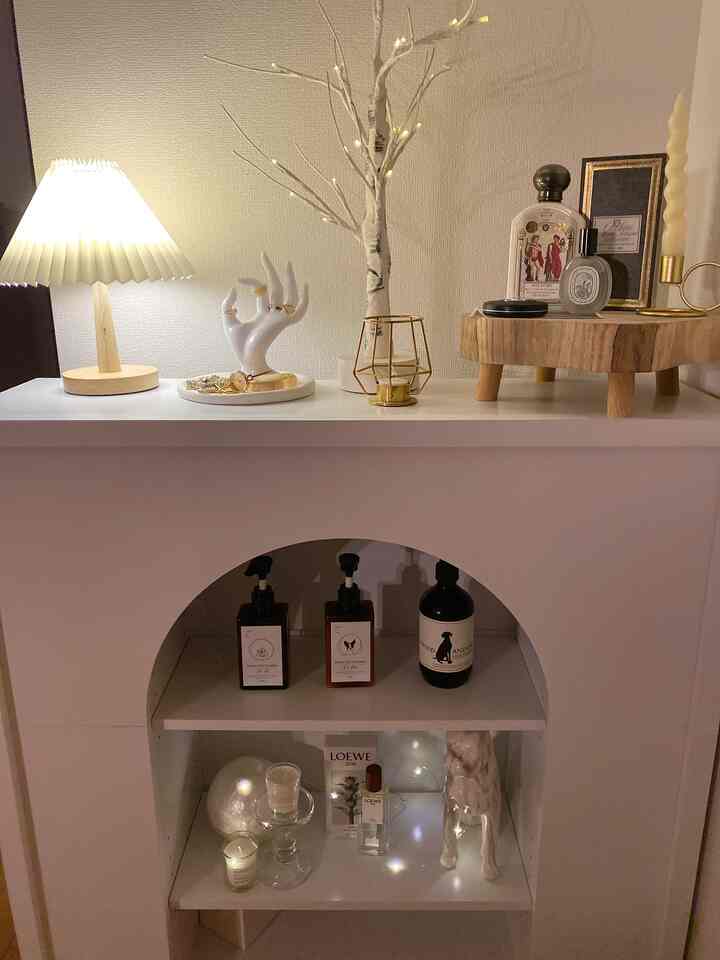 White and wood tone mantlepiece with table lamp and decorative objets creating a cozy ambiance