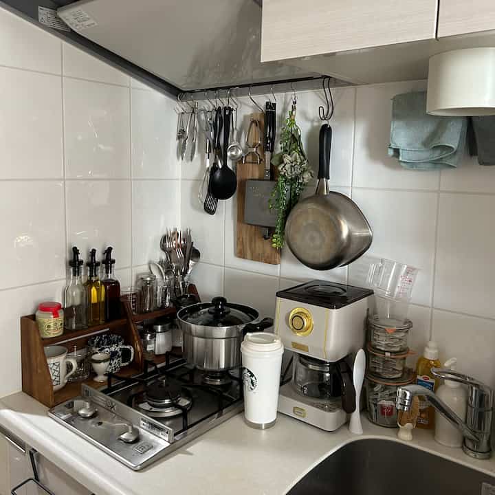 Natural-toned kitchen with coffee maker and utensils neatly arranged on white countertop creating a clean space