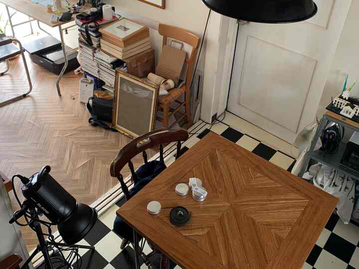 木目調と白のリビングダイニング、ヘリンボーンフロアが特徴的で、テーブルと椅子がやや散らかった印象の空間