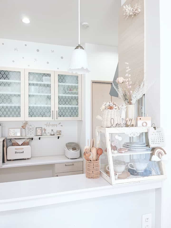 白とナチュラルカラーのキッチン、整ったキャビネットと小物が配置された雰囲気のある空間