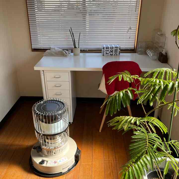 明るいホワイトとナチュラルな木目調の小さなホームオフィス、緑豊かな観葉植物が印象的な落ち着いた雰囲気のインテリア