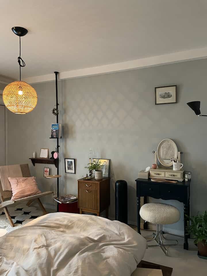 Cozy bedroom with soft gray walls, natural wood furniture, and comfortable bed setup