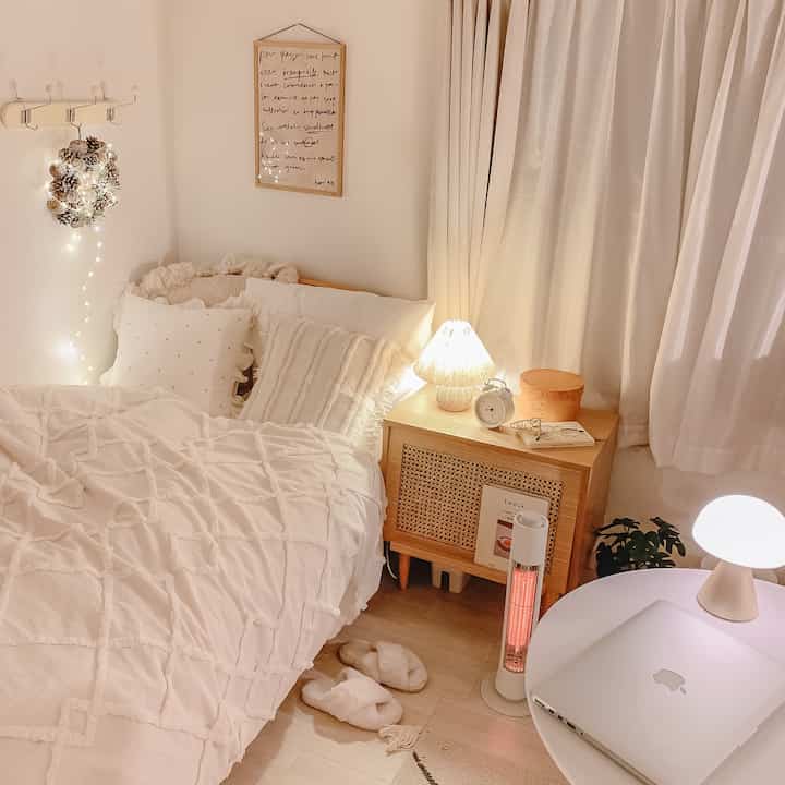 Beige-toned cozy bedroom featuring a bed, side table, and heater creating a warm atmosphere