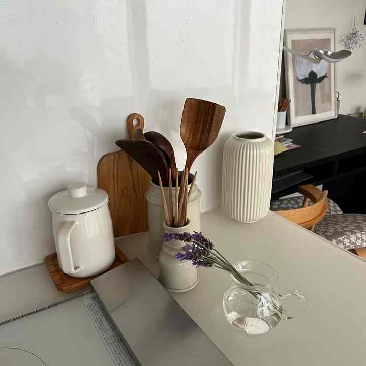 白とナチュラル色調のキッチン、ラベンダーの花と木製調理器具が配置された印象的な空間