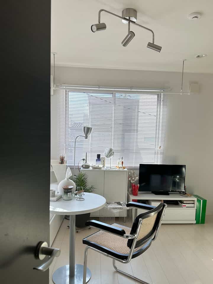 White and silver toned living room featuring a round table, office chair, floor lamp with a clean minimal ambiance