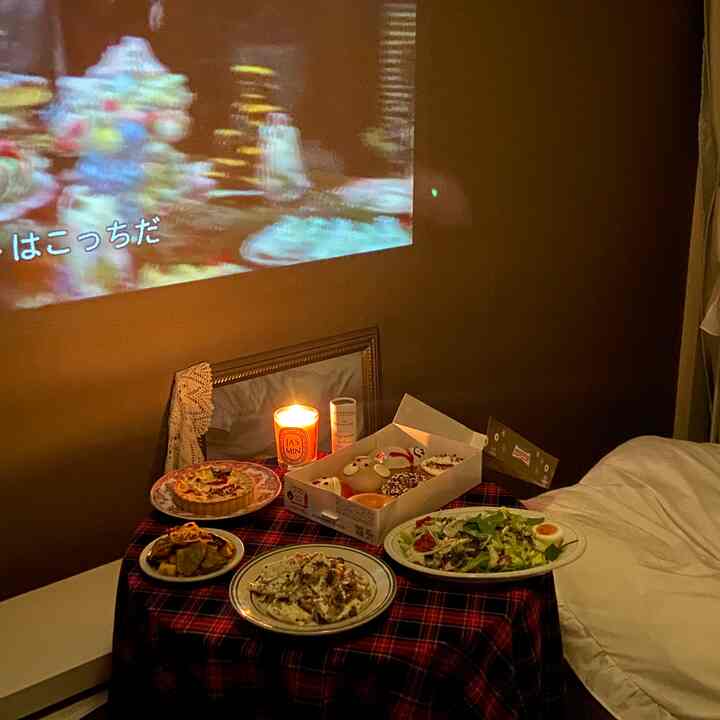 Cozy living room with dark brown walls and white sofa featuring a red plaid tablecloth-covered table topped with candle and various dishes for a home party