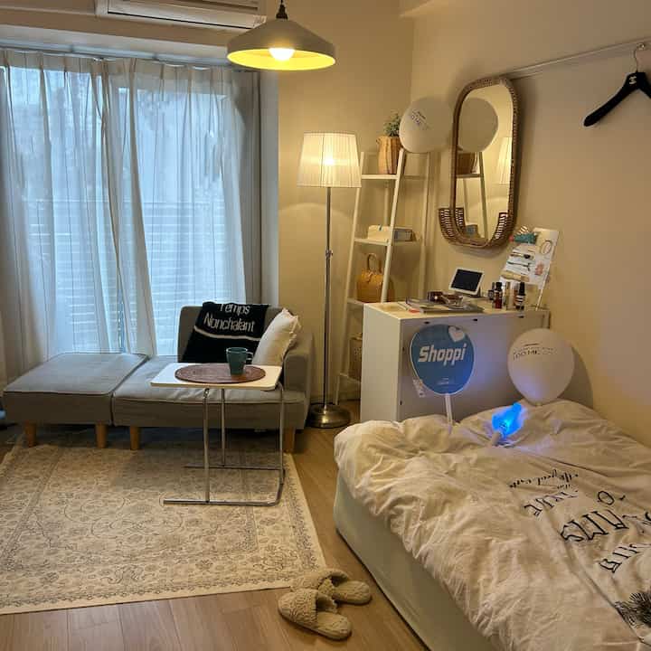 Wood tone flooring and beige-toned furniture in a simple, minimal single household living and bedroom space