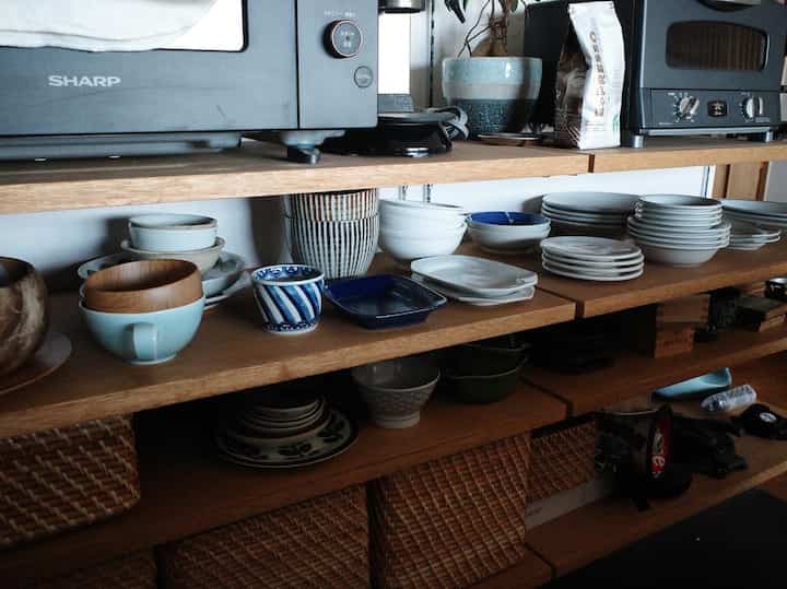 ナチュラルカラーのキッチン、オープンシェルフと無印良品のラタンバスケットが配置された整頓された収納空間