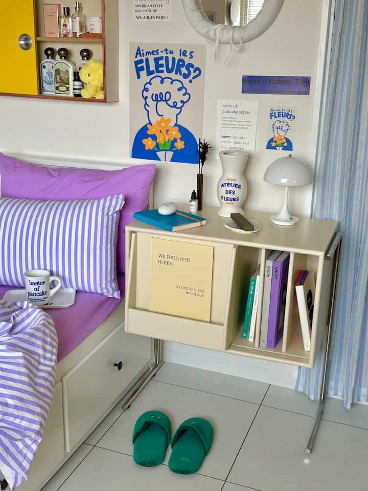 Cozy bedroom featuring purple bedding and a white magazine rack side table