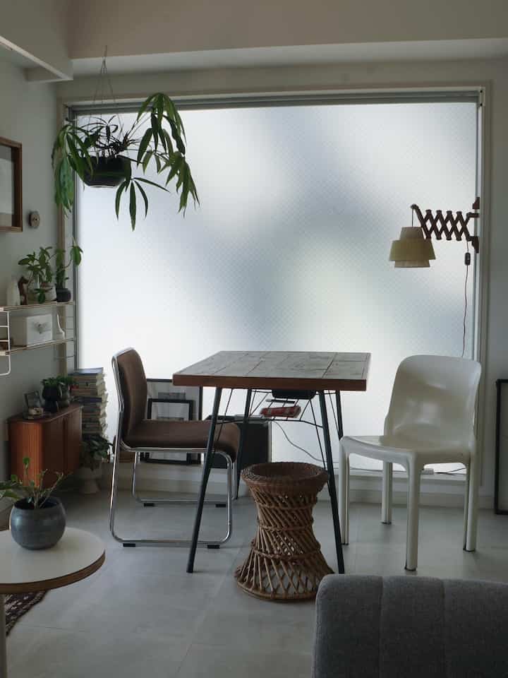A calm beige and white toned dining room featuring a natural wood dining table and chairs arranged by the window creating a cozy atmosphere