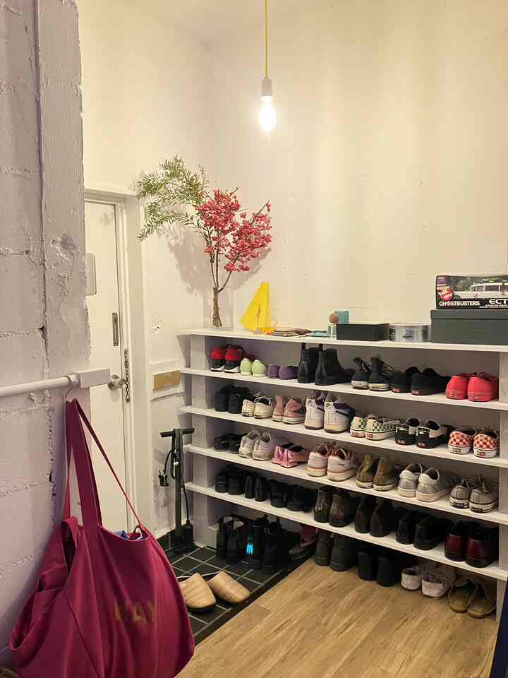 白い壁と木目調の床がある二人暮らしの玄関、整理された多目的なシューズラックが配置された雰囲気のある空間