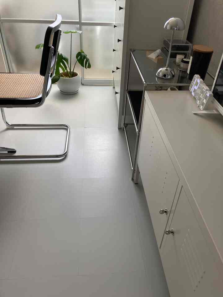 White floored, narrow modern space featuring silver chair and plant with clean and minimal setup