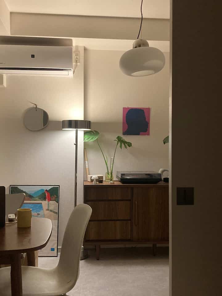 白と茶色のトーンの寝室、ペンダントライトとフロアランプ、LPプレーヤーが配置された雰囲気のあるインテリア