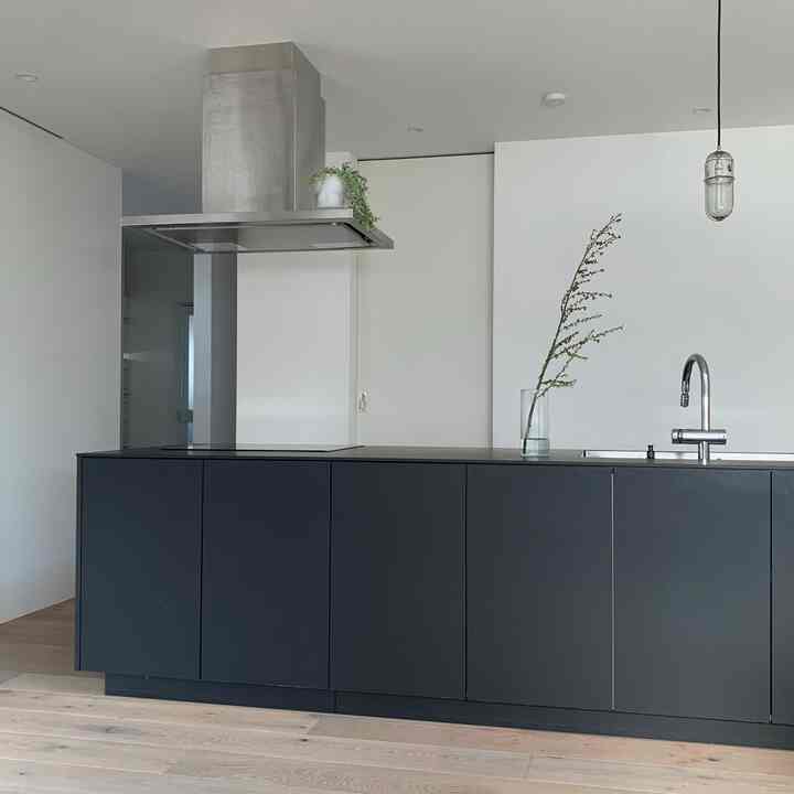 黒いキッチンキャビネットと白い壁が調和したシンプルでモダンなキッチンのインテリア