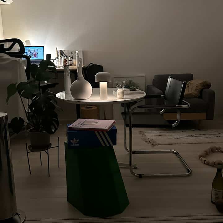 ホワイトとブラックの調和が美しいモダンなリビング、デスクとソファが配置され、落ち着いた夜の在宅勤務空間