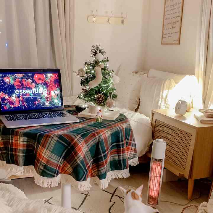 白とナチュラルトーンのリビング、クリスマステーブルクロスと小さなツリー、猫がいる暖かい冬の空間