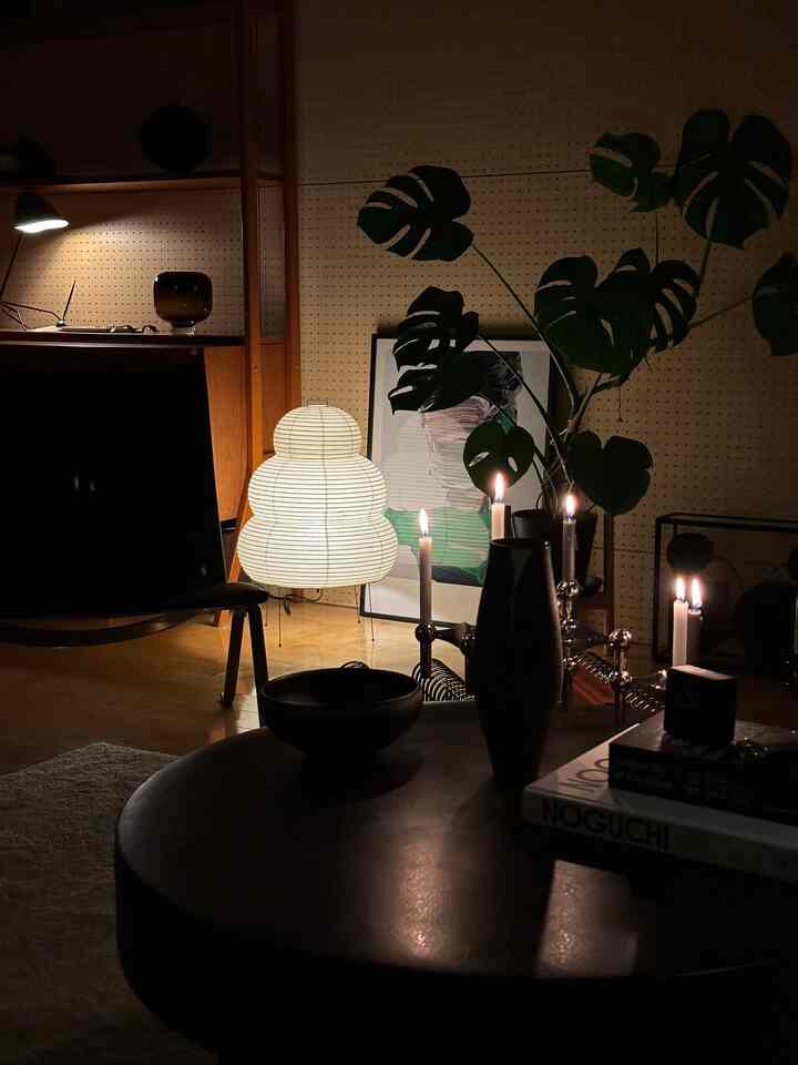 暖かい照明とキャンドルのあるモダンなリビング、コーヒーテーブルと大きな観葉植物が配置された空間