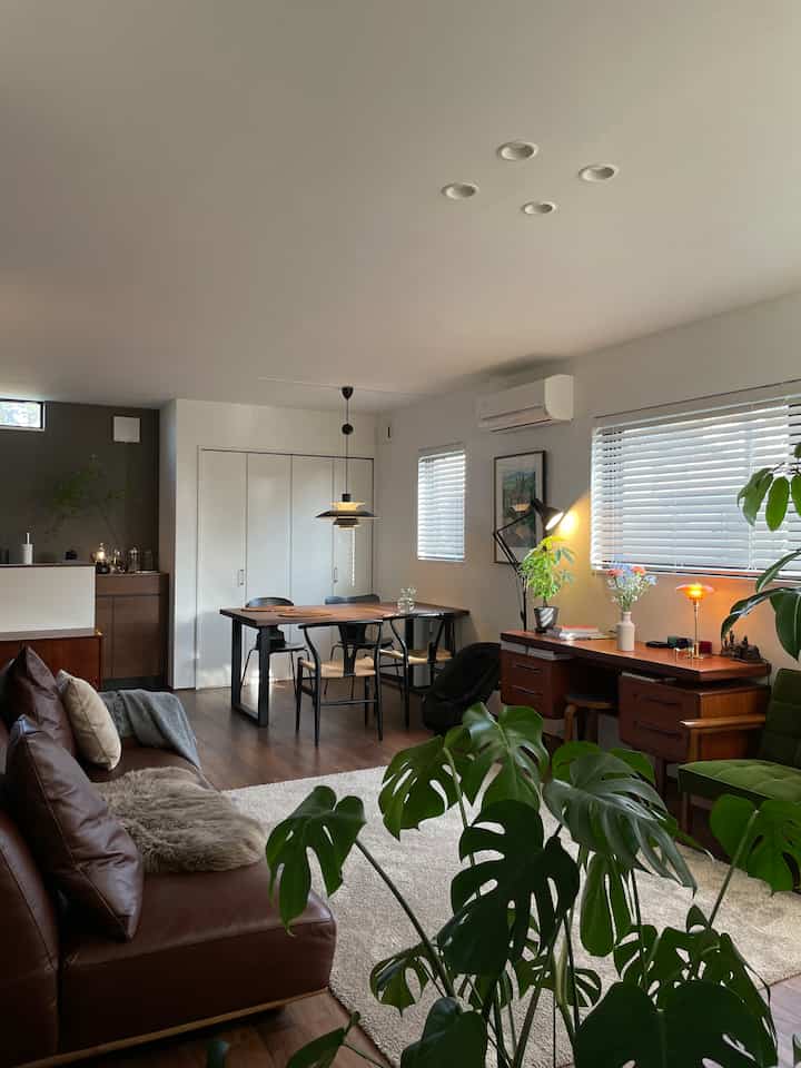 Warm wood-tone living and dining room featuring modern furniture and a pendant light creating a cozy atmosphere
