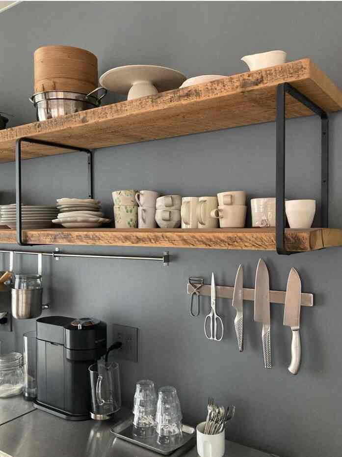 Gray wall background kitchen featuring wood tone open shelves and neatly arranged kitchen knives for a clean aesthetic