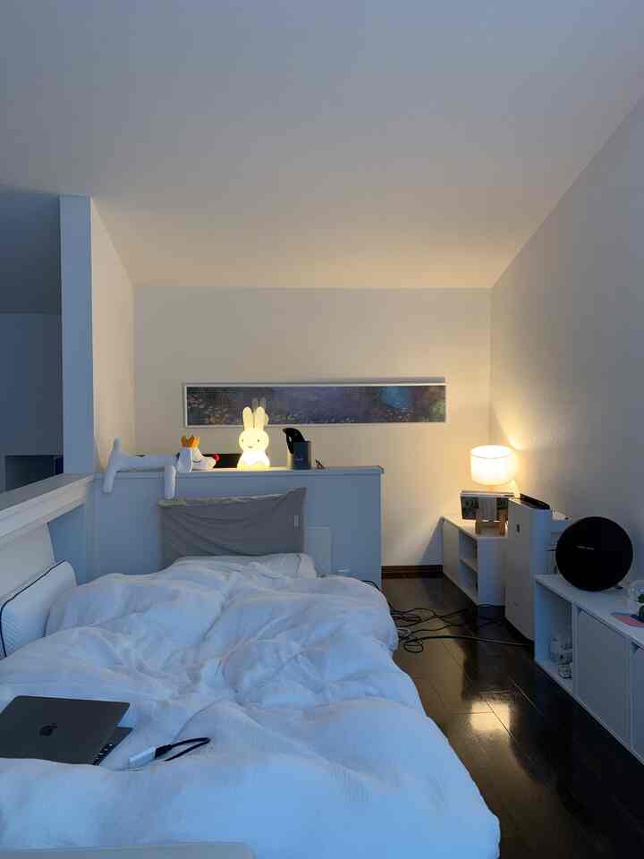 白とダークブラウンのトーンのロフト寝室、ミッフィーライトとテーブルランプが配置されたシンプルでナチュラルなインテリア