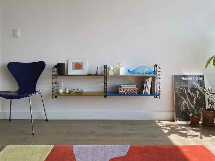 Navy chair and colorful vintage accessories arranged on minimalist wall in a living room space