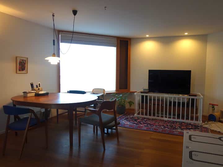 白と茶色のトーンが特徴的なリビング、無垢材のダイニングテーブルとベビーゲートが配置された赤ちゃんと暮らすモダンな空間