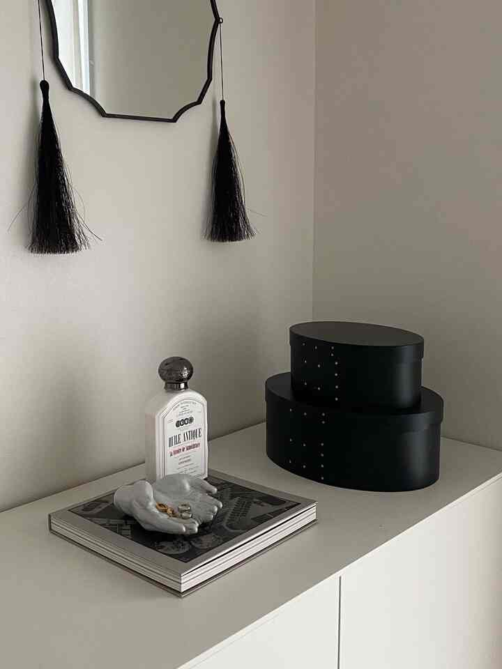 Simple storage space in white and black tones featuring shaker boxes and custom accessory trays in a modern interior