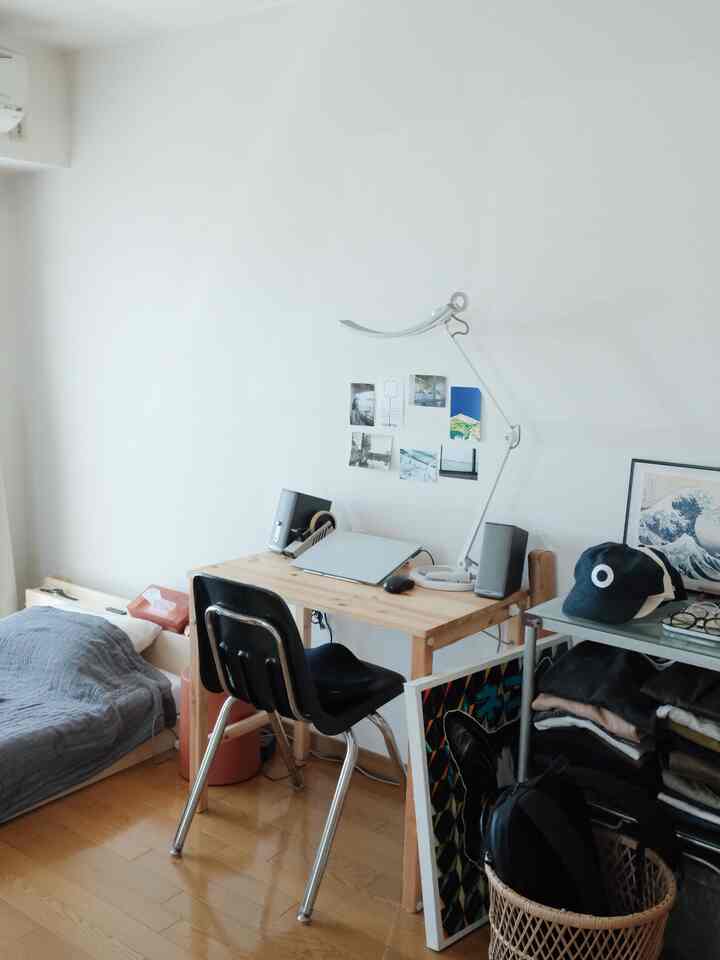 白い壁と木目調の床が調和する一人暮らしのワンルーム、シンプルなホームオフィススペース