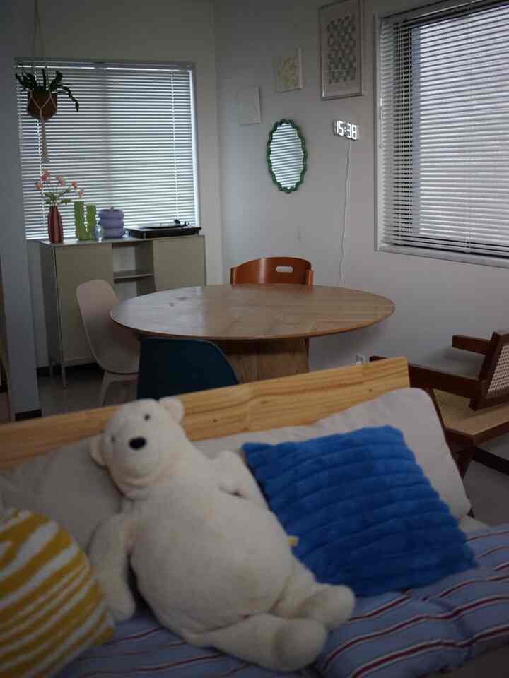 白い壁と茶色の丸いダイニングテーブル、色とりどりの椅子が配置された、日当たりが悪いダイニングルームの雰囲気のあるインテリア