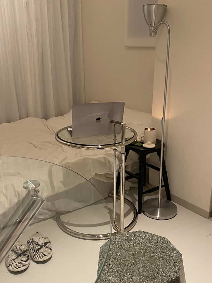 白とシルバーのトーンの寝室、ベッドとナイトテーブル、フロアランプが配置されたモダンな空間