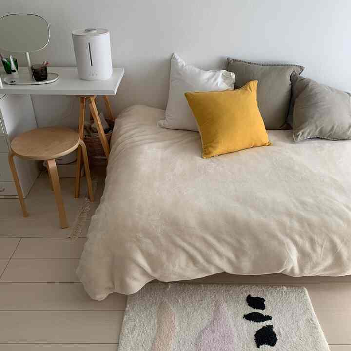 ベージュとホワイトのトーンの1K寝室、クッションとベッドがソファの役割を果たす居心地の良い空間