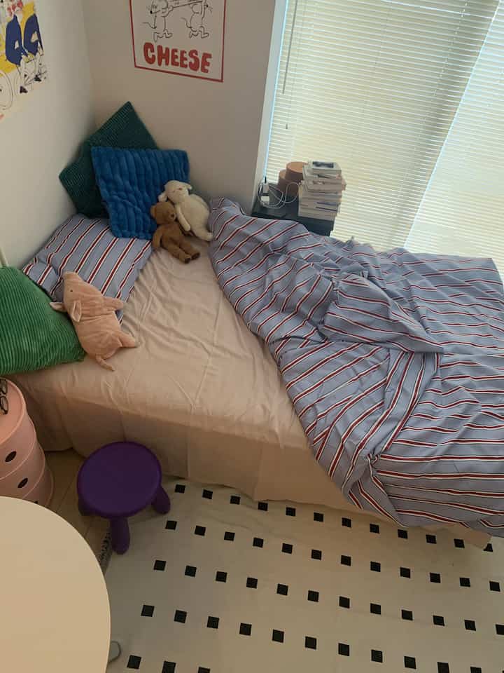 Natural-toned 6-tatami bedroom with blue striped duvet cover, colorful cushions and stuffed animals creating a cozy atmosphere