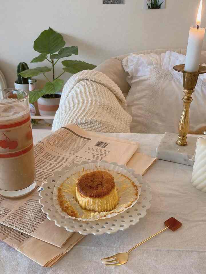 ベージュとホワイトの色調のリビング、アームチェア、クッション、キャンドル、デザートとドリンクが配置された雰囲気のあるおうちカフェ空間