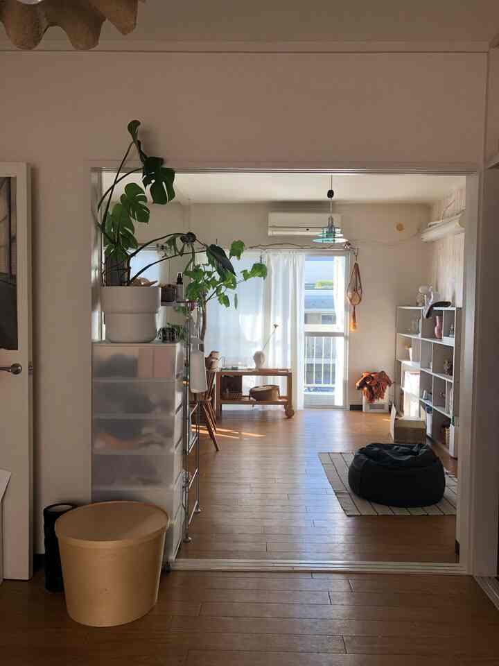 ナチュラルカラーの床と窓がある多目的空間、ビーズクッションや本棚、収納が配置された明るく整った部屋